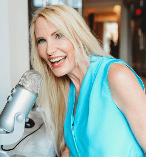 Mia Hewett in a vibrant blue top recording a podcast with a professional microphone, showcasing her engaging personality and expertise in media communications.