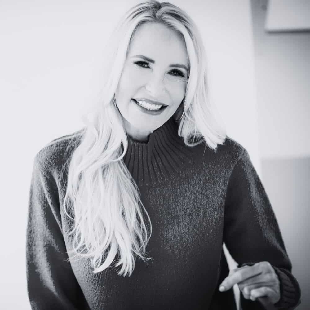 Warm smile of Mia Hewett, lifestyle and branding photographer, showcasing her friendly personality and professional photography work, in a black and white portrait.